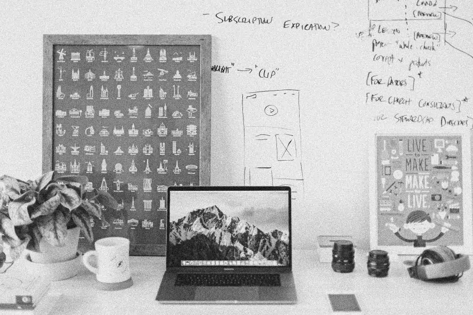 An office wall and desk. On the wall are illustrations and work related notes