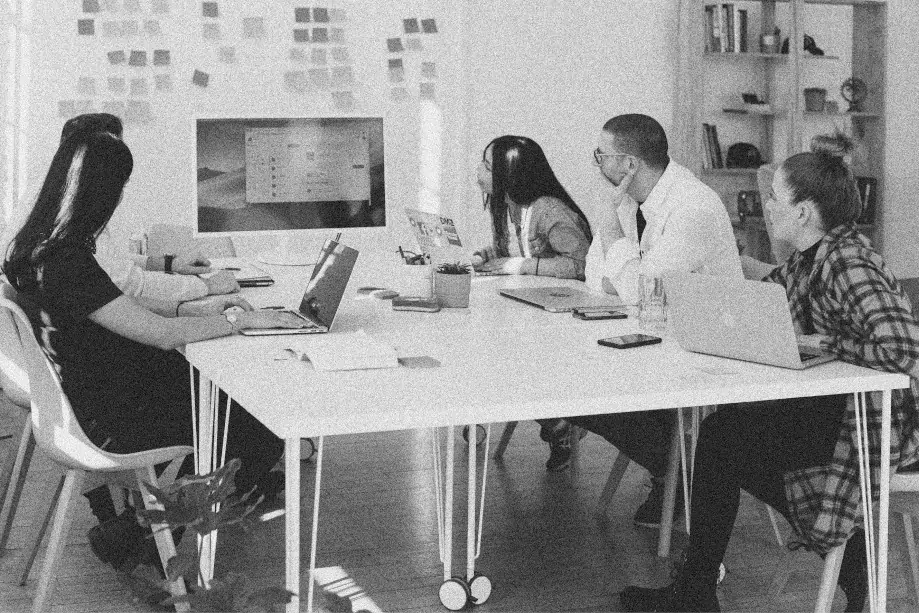 An design team discussing the design displayed on a wide monitor screen.